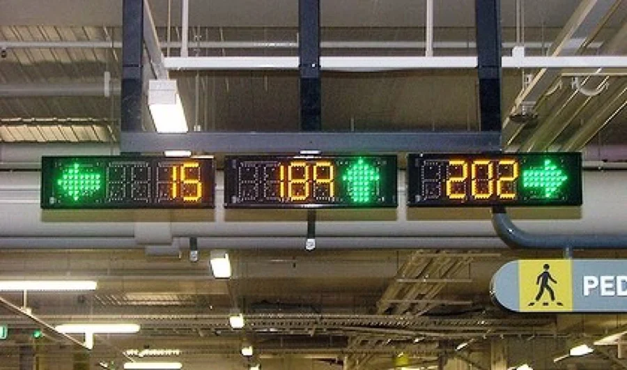 Automated parking guidance system indicator lights showing green open and red occupied bays along a parking garage aisle