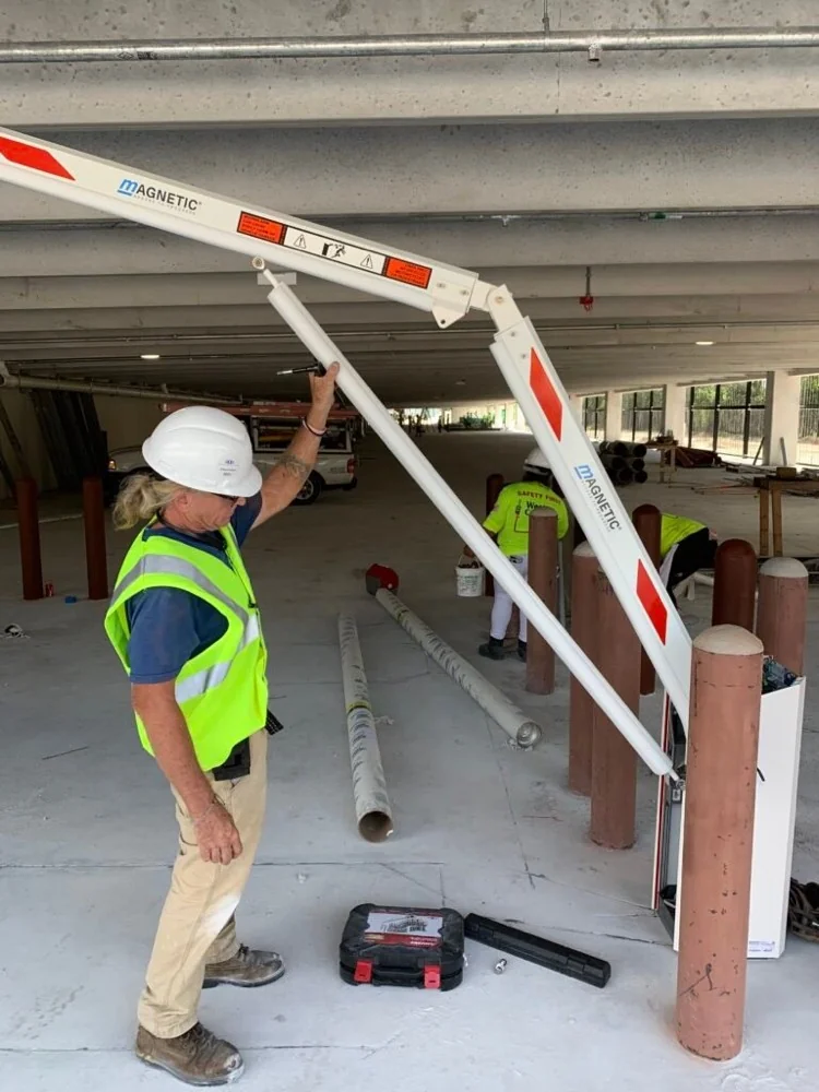 Kyosis technician installing a Magnetic Autocontrol barrier gate arm at a parking garage entry lane